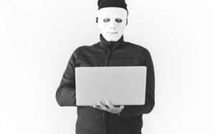 Man in mask hacking laptop computer