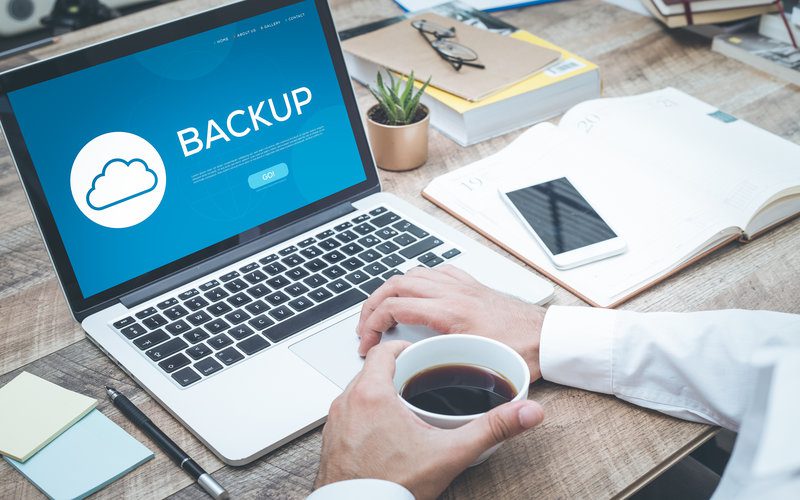 Man with laptop that says Backup on screen