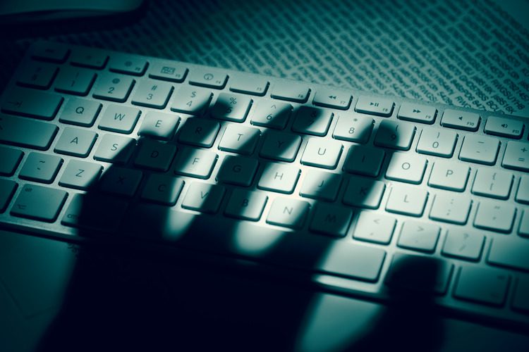 Shadow hand over computer keyboard